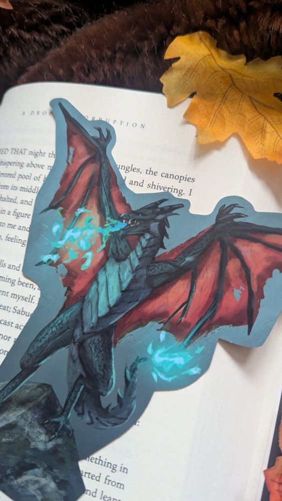 Wyvern bookmark picture. The wyvern has see through red wings with claws. The creature has teal scales and is standing on a rock