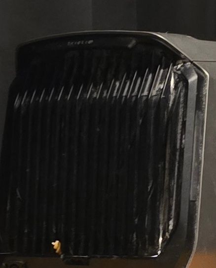 A photo showing the back filter of my air conditioning unit with a piece of pasta sticking up from the bottom part, wedged in the downward-style slots. 