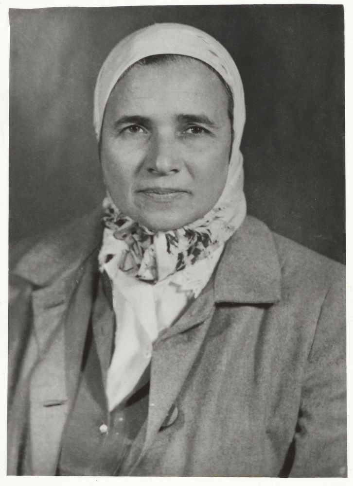 Black and white photo of Zahira Abdin. An Egyptian woman dressed in a shirt, coat and pale headscarf.