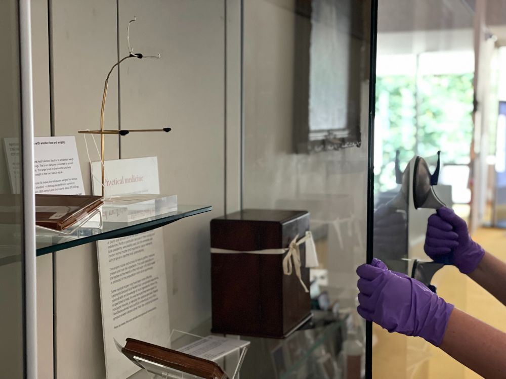 A partially open display case with a person moving the case cover closed. 