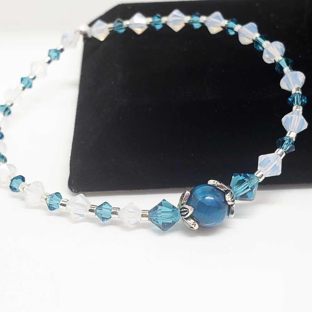 Size 6.25" BTS Jin Wootteo inspired Bracelet. Includes 4mm Genuine Bicone Swarovski Crystals in white opal, 5mm/4mm/3mm Swarovski Crystals in Indicolite, a Blue Green Tiger Eye Gemstone with Sterling Silver endcap beads and galvanized sead beads. Finished with a sterling silver crimp bead to hide the knot. My bracelets are all hand-made and I am an ARMY.