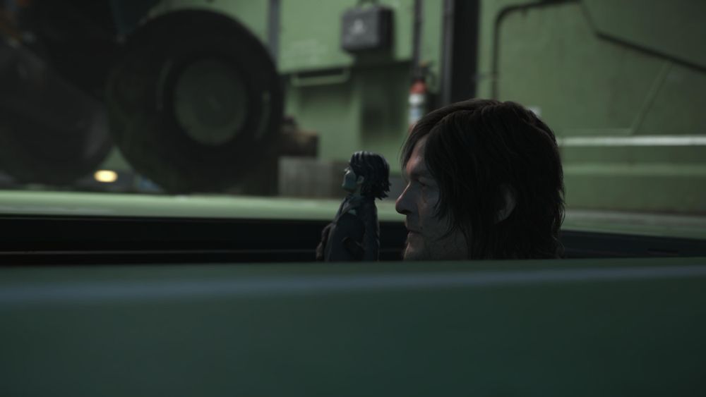 A screenshot from Death Stranding 2. Sam (a human) and Dollman (a puppet) are appearing from a hole in the floor, looking left. 