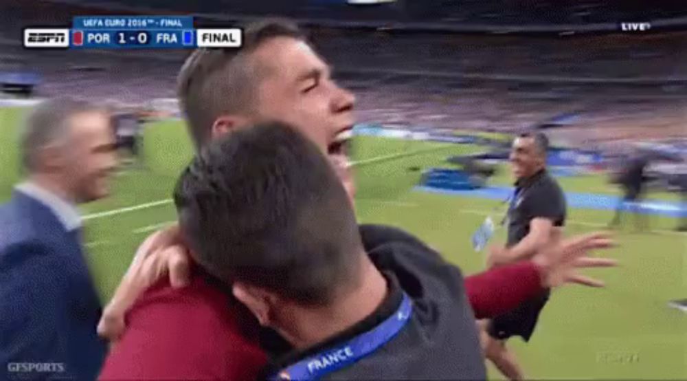 a man with a france lanyard around his neck is hugging another man on a soccer field