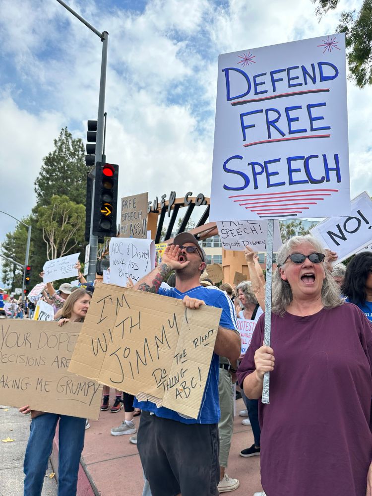 Three people holding signs 