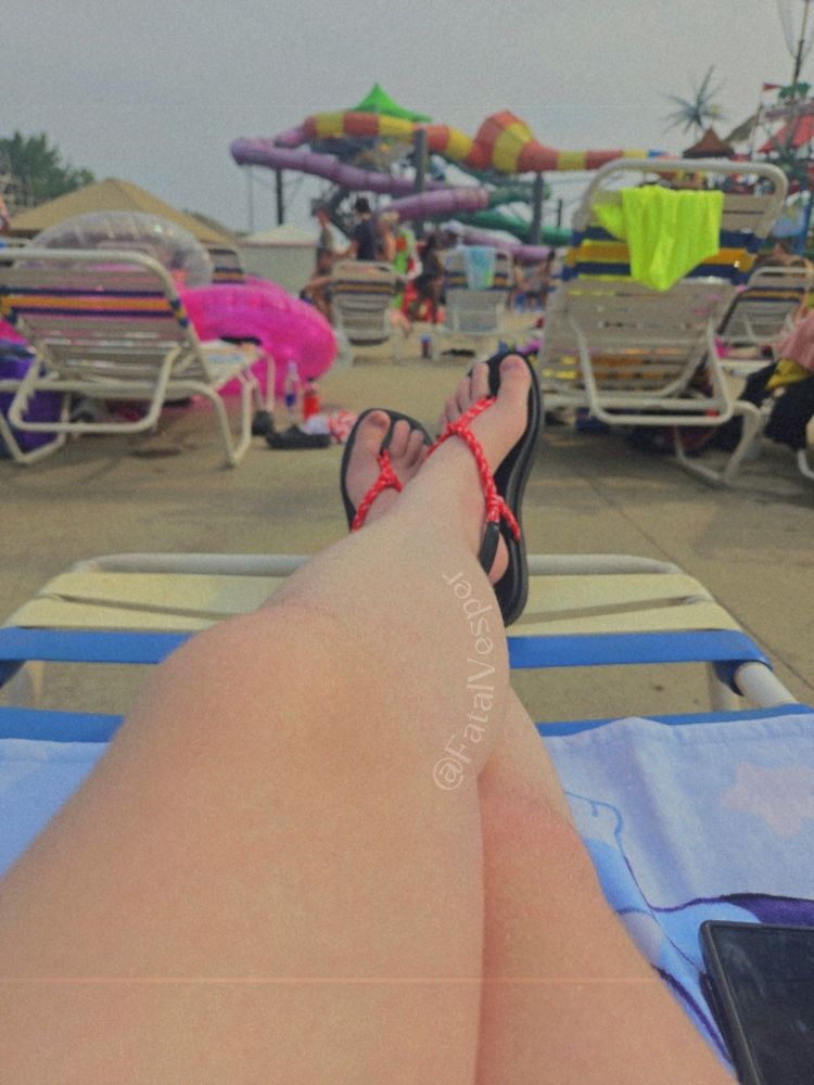 A pic of my legs and feet. Its evident im sitting in a beach chair with a towel and there are lots of beach chairs and towels and waterslides in front of me