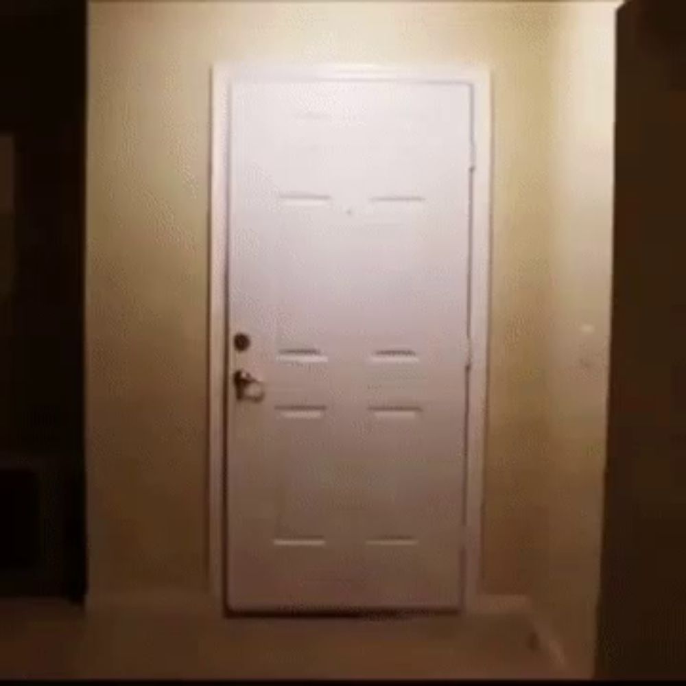 a white door is open in a hallway with a light on it .