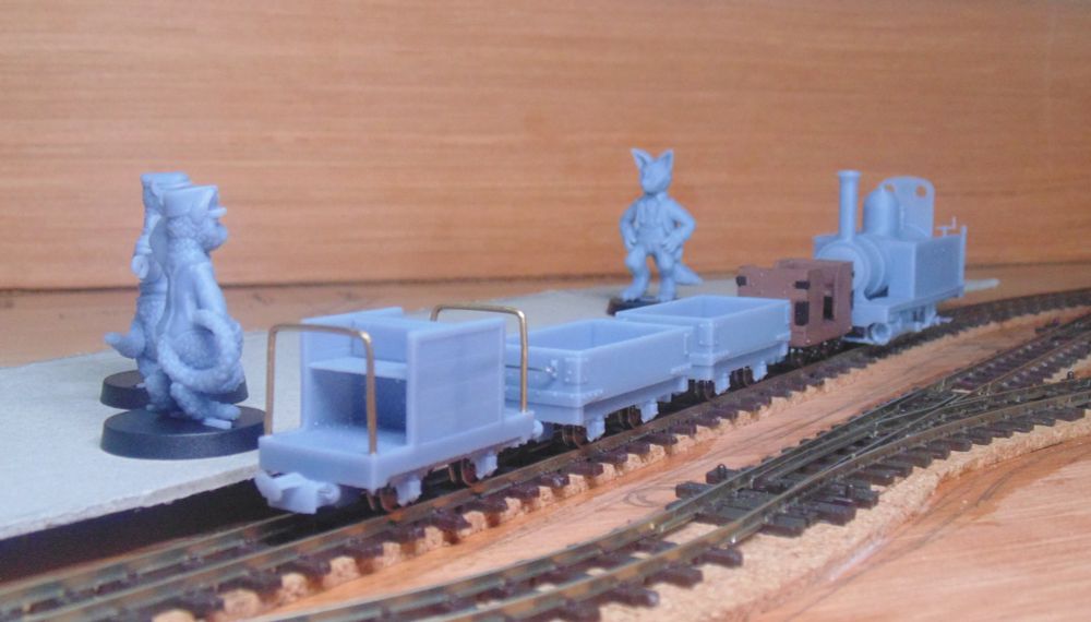 Theo the Fox standing alongside Heywood 0-6-0T "Herring Gull", on a test train with a couple of wagons. Milkdrop the Station Cat watches nearby as Randell the Workshop Ferret pops by to make sure everything is in order.