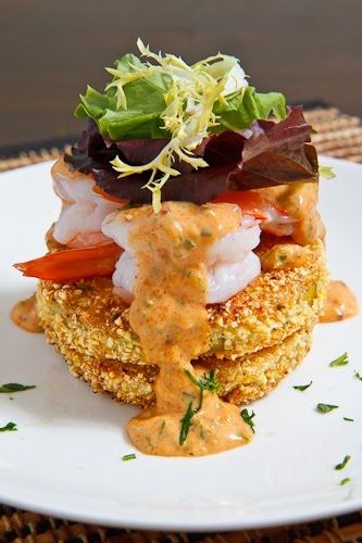 A stack of two fried green tomatoes topped with blackened shrimp and baby salad greens.