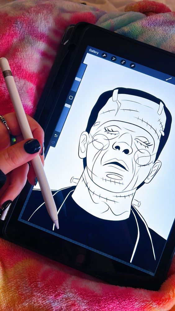 Hand holding a pen with an iPad screen showing a drawn frankensteins monster