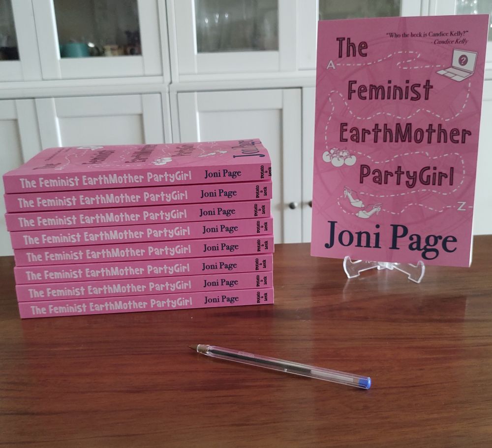 A stack of The Feminist EarthMother PartyGirl, a pen, and a copy of the book on a stand.