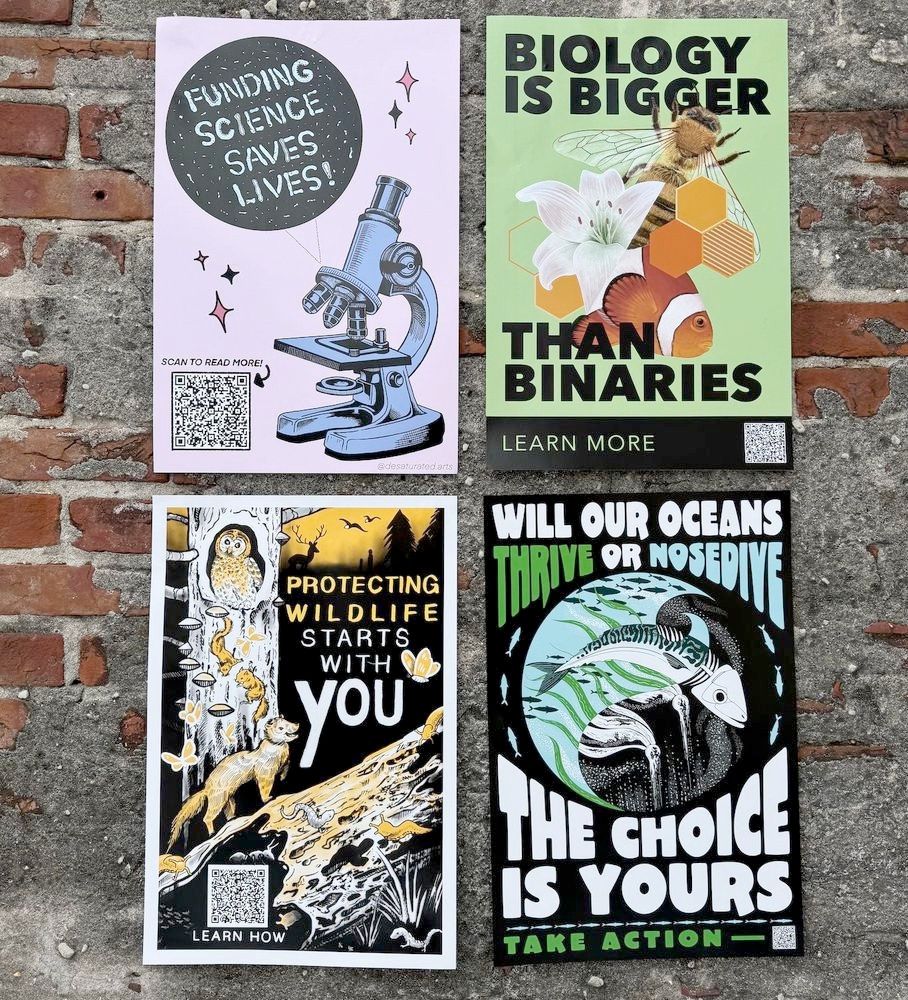 4 12x18 inch posters on a brick and concrete wall. The top left is pink and says funding science saves lives, written in microbes, next to a microscope. The one on the right says Biology is bigger than binaries, with a fish, a lily, and a bee. The bottom left says Protecting wildlife starts wtih you, with a bunch of adiorable woodland creatues in yellow, white and black, including an owl, fungi, a... um. weasel? salamanders, butterflies, slugs, and a rotting log. The bottom right says Will our oceans thrive or nosedive the choice is yours, with the ocean represented in a circle, half of which is dead and half of which is alive, including kelp and a mackerel 