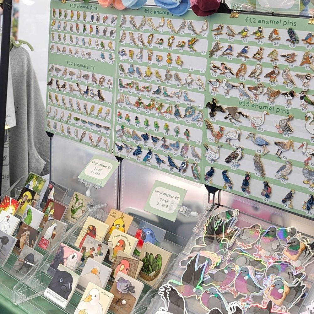A picture of a convention table showing bird stickers and bird enamel pins
