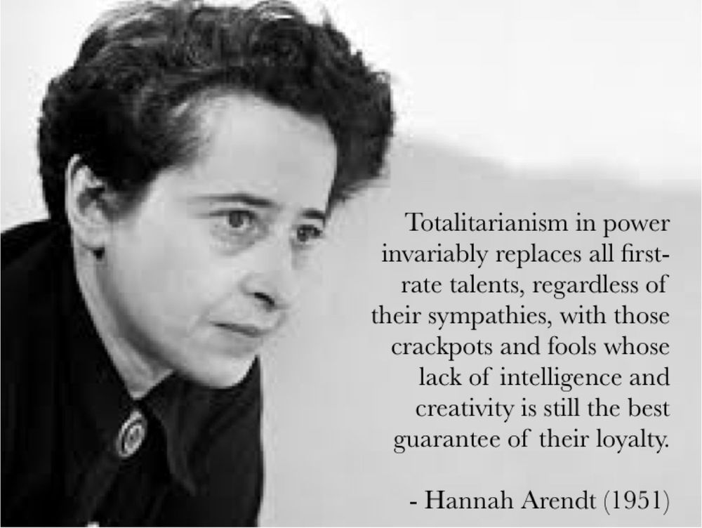 Black-and-white image of Hannah Arendt with a contemplative expression. She has short, dark hair and is wearing a dark top with a brooch at the collar.
