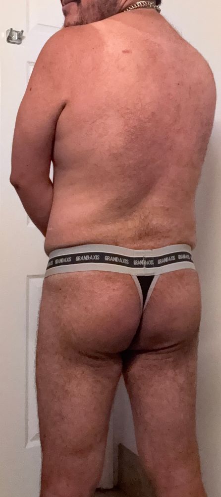 Man with his back turned to the camera, showing off a thong.