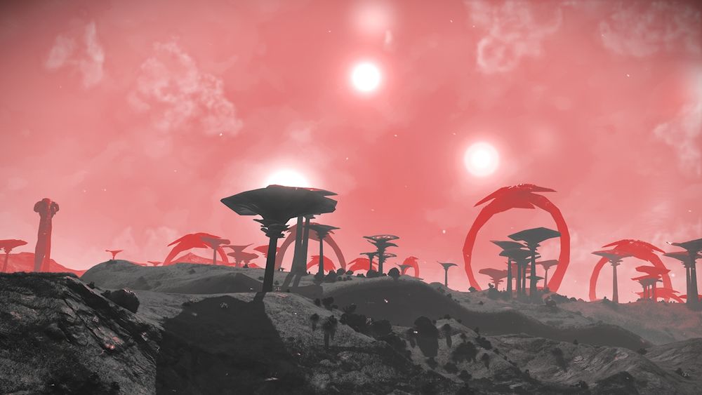 Image of an ash coloured landscape with a red sky, the sky has some light cloud cover and 3 sun like objects, some of the plants and structures on the ground have a red hue to them from th sky the further into the background