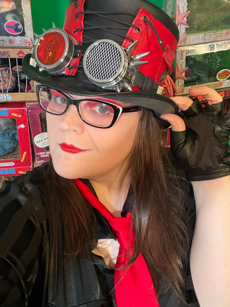 Stephanie Sterling in red/black corseted hat, red tie, black pinstripe dress top, black gloves and red makeup. 