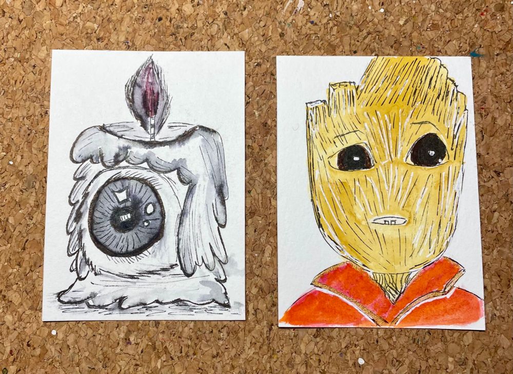 Zwei kleine Kärtchen, auf der linken Karte Sketch einer Kerze mit Auge und auf der linken Sketch von I am Groot/Marvel. Alles liegend auf einem Schreibtisch mit Korkunterlage