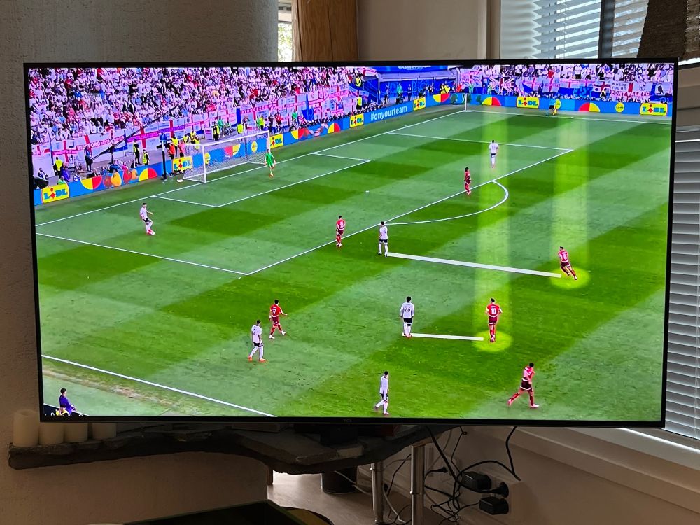 A television with a portion of a soccer game on it. Ons team in, the other in red. Using production effects, two players in red are spotlit and lines connect each of them to a player in white.