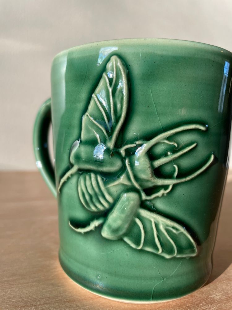 Green crackle mug with a rhinoceros beetle.