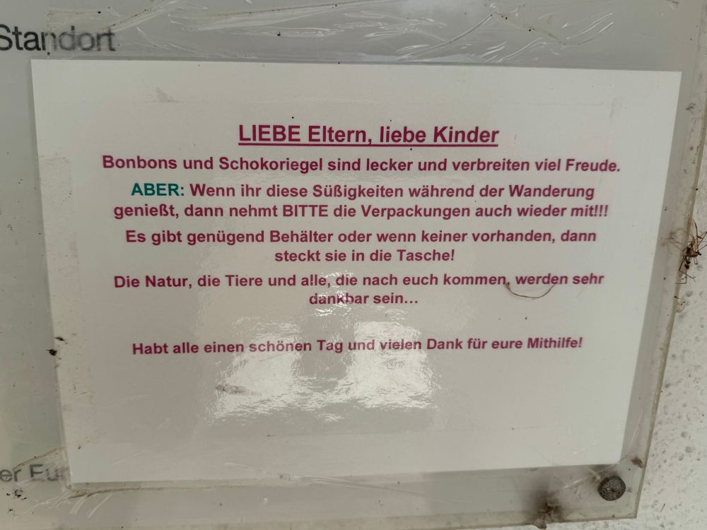 Hinweisschild mit Bitte an Eltern und Kinder, Süßigkeitenverpackungen während der Wanderung mitzunehmen, um Natur und Tiere zu schützen