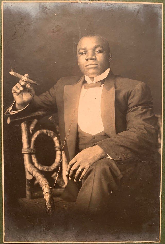 Canadian heavyweight boxer Sam Langford sitting in a chair holding a cigar ca. 1900s 