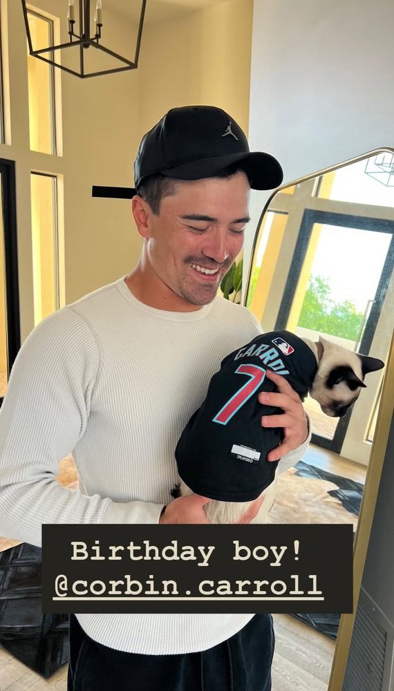 Corbin Carroll holding a Siamese cat which is wearing a Carroll jersey. He’s smiling. The text says birthday boy! 