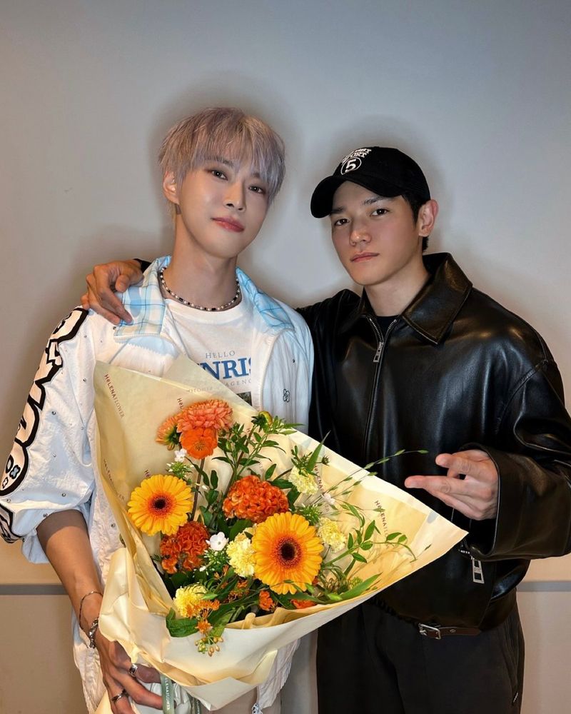 Doyoung and Taeyong backstage after Doyoung’s solo concert. Doyoung is holding a large bouquet of orange flowers. Taeyong has an arm around Doyoung’s shoulders. 