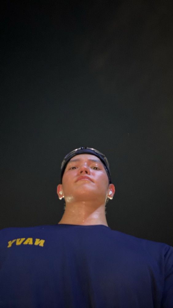 Sweaty Taeyong taking a selfie from a very low angle. He’s wearing a NAVY t-shirt and has AirPods on, likely having just finished a run. 