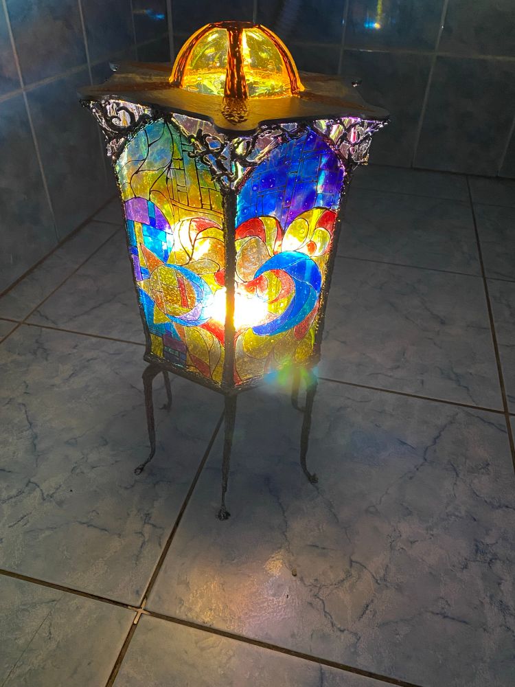 A lantern with a stained glass that has sun and moon on it. Standing on 6 legs with small paws