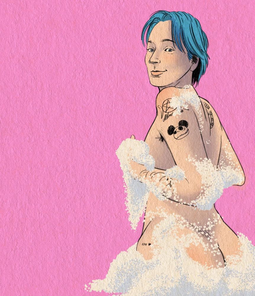 An individual with short blue hair is covered in soapy suds set against a solid pink backdrop, looking at the viewer coyly. Multiple tattoos adorn their skin.