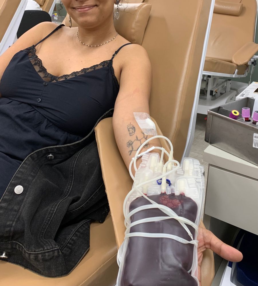 uma foto minha deitada em uma cadeira com vestido preto segurando uma bolsa de sangue 