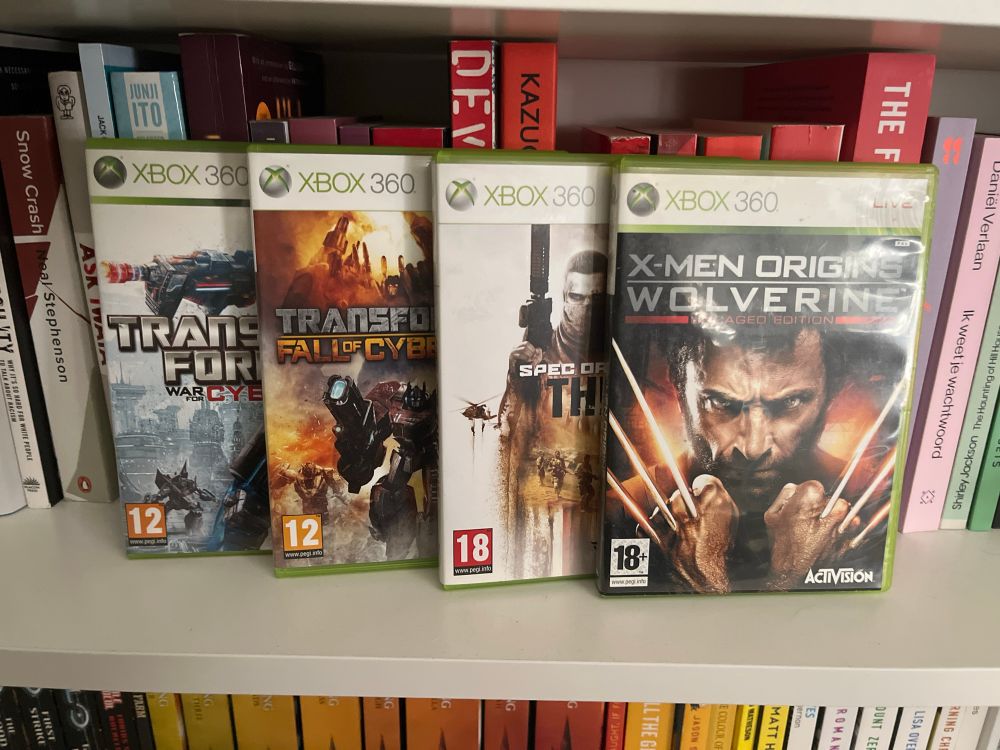 Displayed are Xbox 360 copies of Transformers: War for Cybertron, Transformers: Fall of Cybertron, Spec Ops: The Line and X-men Origins: Wolverine