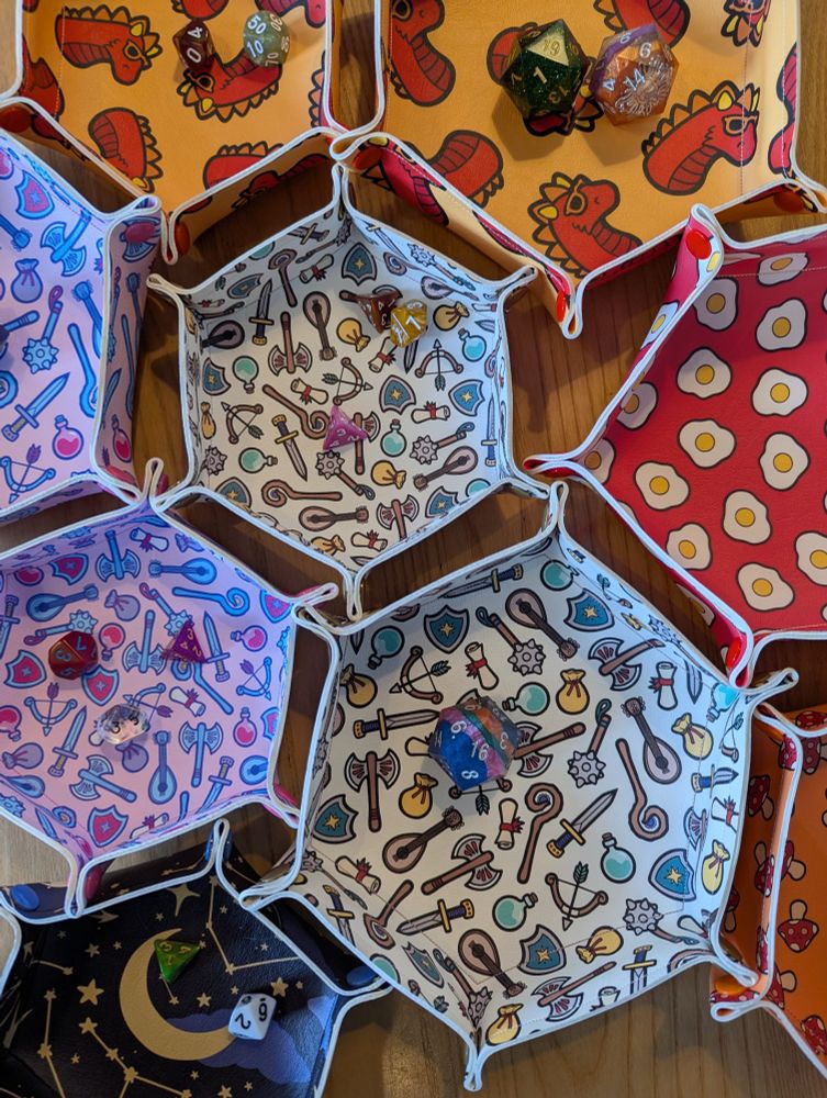 Several dice trays on a table in the Edinburgh board game shop Ancient Robot Games. The vegan leather trays have colourful illustrations