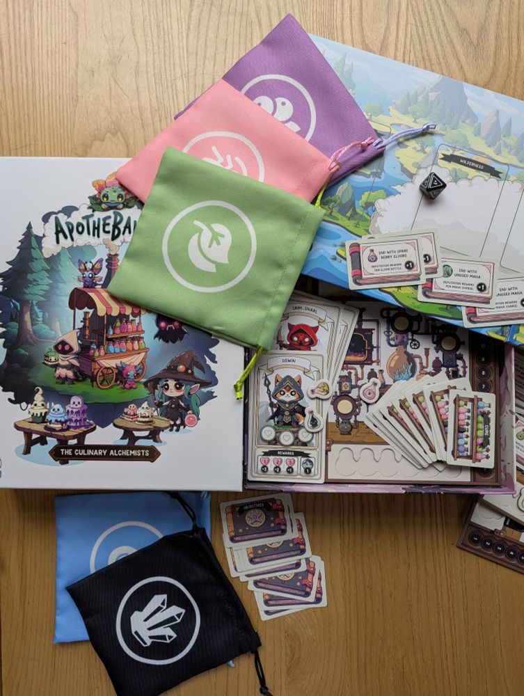 The board game Apothebakery open on a table in the Edinburgh board game store Ancient Robot Games. The game board, cards and canvas bags in different colours are visible from the game box