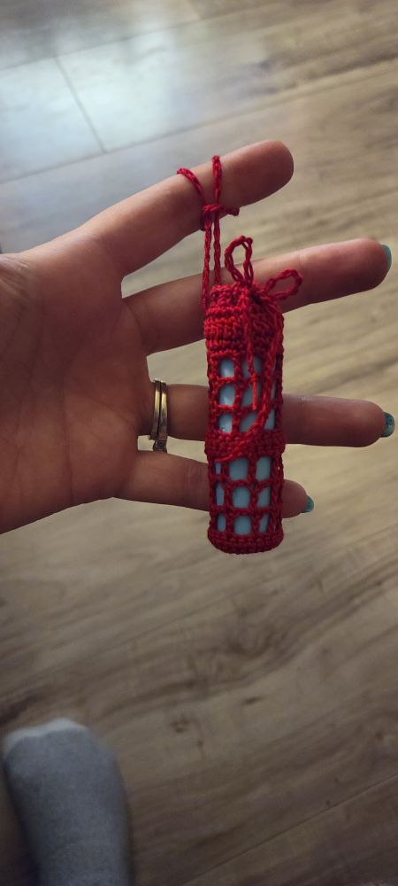 Hand holding a red crocheted case for chapstick