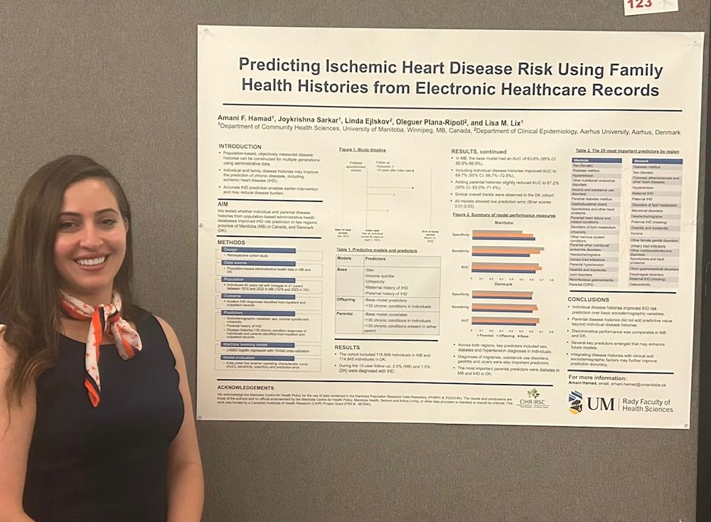 Photograph of a smiling person with dark hair extending below their shoulders, standing beside a poster. The poster contains text, tables and graphs, with headline, Predicting Ischemic Heart Disease Risk Using Family Health Histories from Electronic Healthcare Records. There is a University of Manitoba Rady Faculty logo at the bottom right of the poster.
