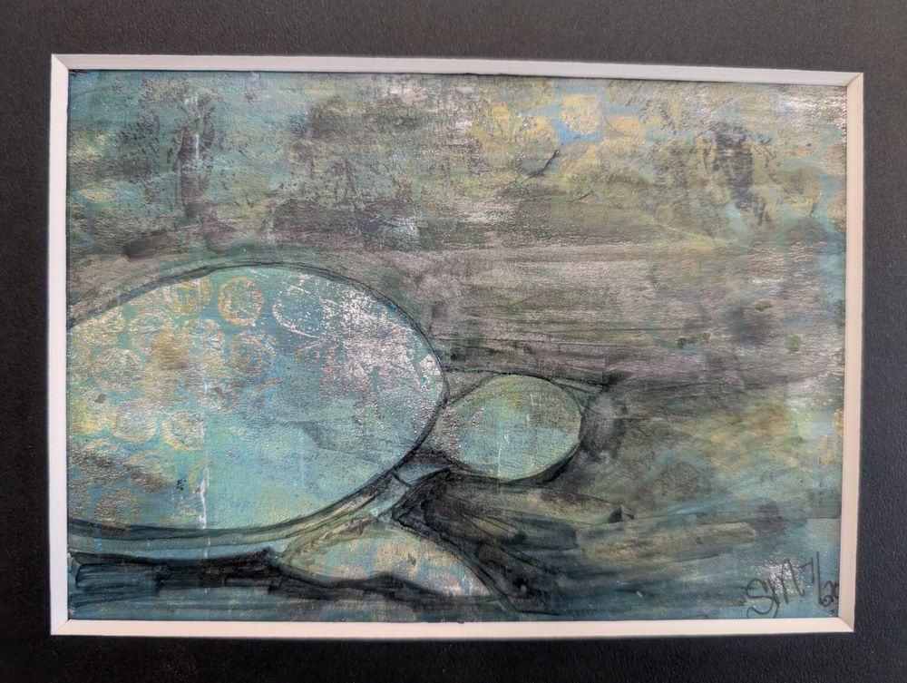 The artwork evokes a tranquil, underwater moment—still and soft, as if time has slowed beneath the surface of a gentle sea. At the lower left of the composition, a large turtle glides forward, its round shell and oval head emerging from the swirling current of colors around it. Its form is simple, almost ghostlike, outlined with faint dark lines that anchor it just enough against the watery background.

The turtle’s shell is textured with faded, circular impressions—like delicate stamps or worn fossil imprints—suggesting age, wisdom, or the quiet history of ocean life. The shell shimmers in pale tones of turquoise, seafoam green, and subtle gold, softened by an overall silvery haze, as if light is filtering down from the surface above.

The head and neck of the turtle stretch gently forward, leading into a vast expanse of abstract water. This space is dominated by layered strokes of blue-gray, green, and muted ochre, blending into each other like currents stirred by slow movement. Here and there, hints of yellow and light blue bubble up through the darker strokes, adding the sense of floating particles or shifting light.

The entire scene feels peaceful—dreamlike, even. There’s no defined background, no coral or fish—just the turtle and the sense of motion through a wide, quiet sea. The texture across the image feels weathered and soft, like something ancient seen through fog or memory.