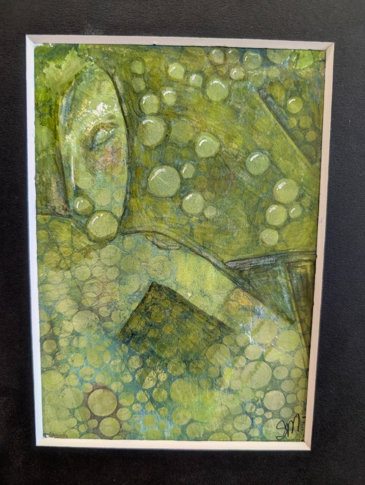 This artwork features a dreamy, abstract figure nestled within a sea of green hues and softly layered bubbles. The entire canvas is dominated by a green palette ranging from moss and olive to chartreuse and hints of blue-green, with a dappled texture throughout. The background consists of overlapping translucent and opaque circles—reminiscent of bubbles or cells—scattered across the surface in varying sizes and opacities. Some circles are highlighted with white accents, giving them a glossy, dimensional look, almost as if they’re glistening or catching light.

Emerging subtly from the layered texture is the outline of a reclining figure. On the left side of the canvas, a stylized head is visible in soft profile. The facial features are simplified and peaceful—only one closed eye is defined, giving the figure a serene or meditative appearance. The head tilts slightly downward as if in sleep or contemplation.

The rest of the body is abstract and gently contoured, blending seamlessly into the surrounding patterns. A diagonal shape in the lower center resembles a bent elbow or arm crossing the torso. The lines are delicate and sketch-like, partially obscured by the surrounding textures and circles, making the figure feel like part of the landscape—neither fully separate nor fully hidden.

The atmosphere of the piece is tranquil and immersive, evoking a sense of quiet rest, submersion, or connection with nature. The bubbles add both whimsy and depth, creating the impression of floating, dreaming, or being underwater. 