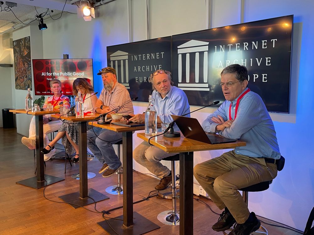 Five people on a panel discussion about “AI for the Public Good” with logo “Internet Archive Europe” behind them. 