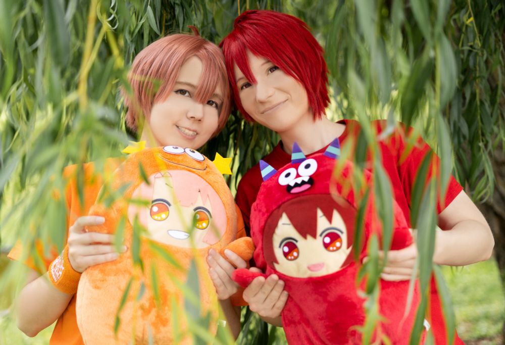 Me cosplaying as Mitsuki and Yoru cosplaying as Riku from IDOLiSH7, both of us are holding a Dekamon of our characters.