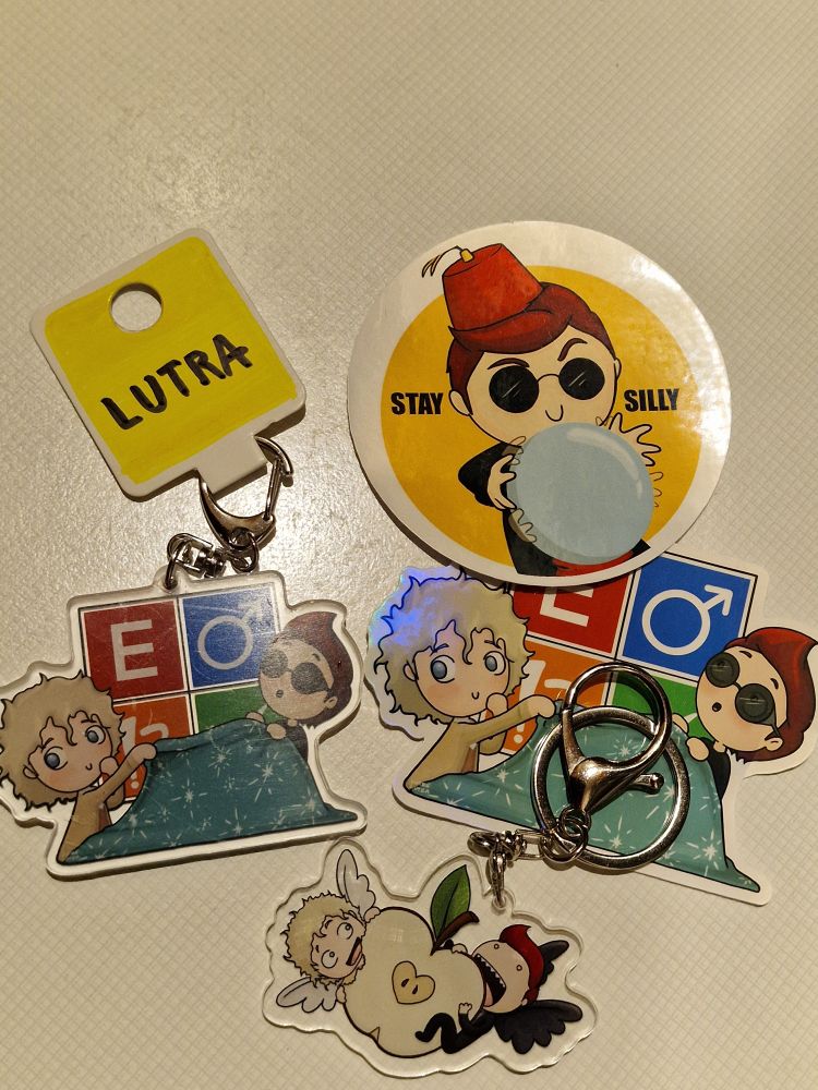 Two Good Omens themed stickers and keychains by Lutra.