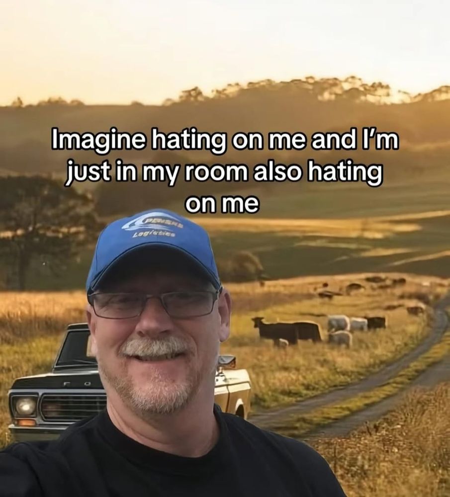 image of a smiling middle aged white guy with glasses and a blue hat, edited into the foreground of an image of a bunch of cows standing in a field at sunset (sunrise? idk) and a dirt road with an old truck. caption is "imagine hating on me and I'm just in my room also hating on me"