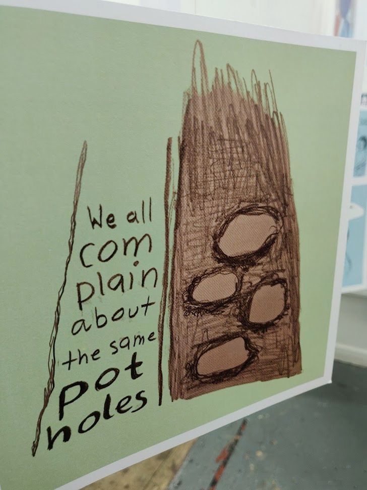 Artwork featuring text on a mint green background and a drawing of a pothole ridden street. The text says ‘We all complain about the same potholes.’