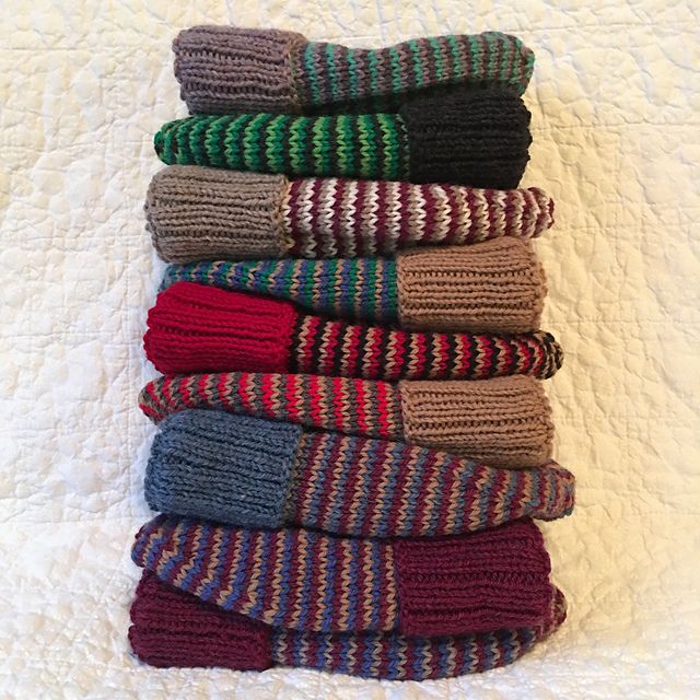 A stack of colorful striped handknit hats with an off-white background.

No particular pattern was used for these, I've made so many charity hats that I can do it on auto-pilot. The striping technique is called helix stripes, and there are many various tutorials to be found via google &/or youtube. 