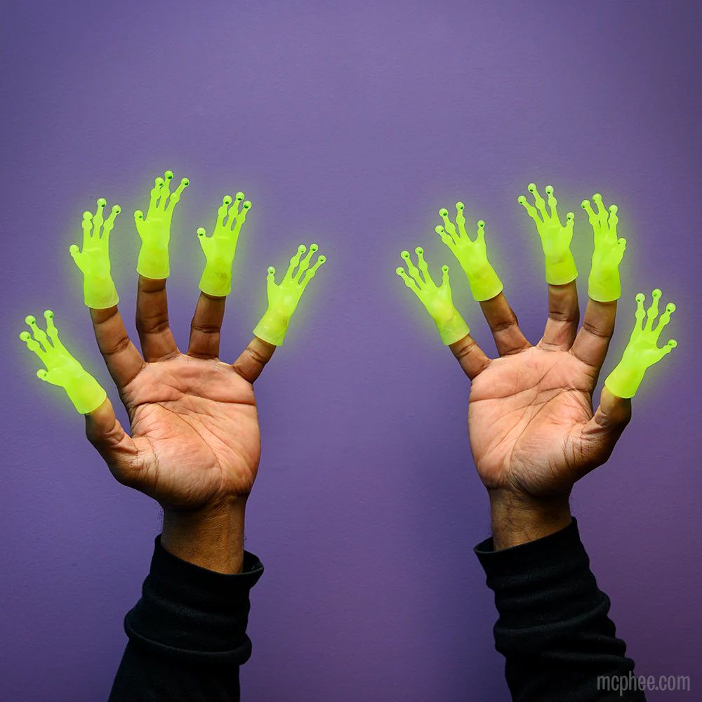 Two hands facing palms out stick out from the bottom of the screen. Every finger has a glowing knobby, green alien hand finger puppet on the tip. The background is purple. 