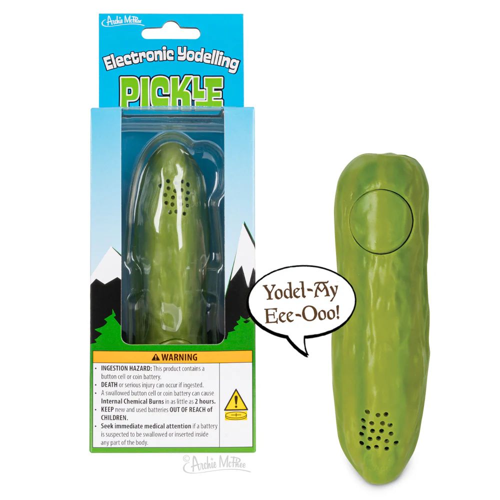 A green electronic pickle with a button. There is a world balloon with "Yodel-Ay-Eee-Ooo!" in it. Behind the pickle is the same pickle in its package. 