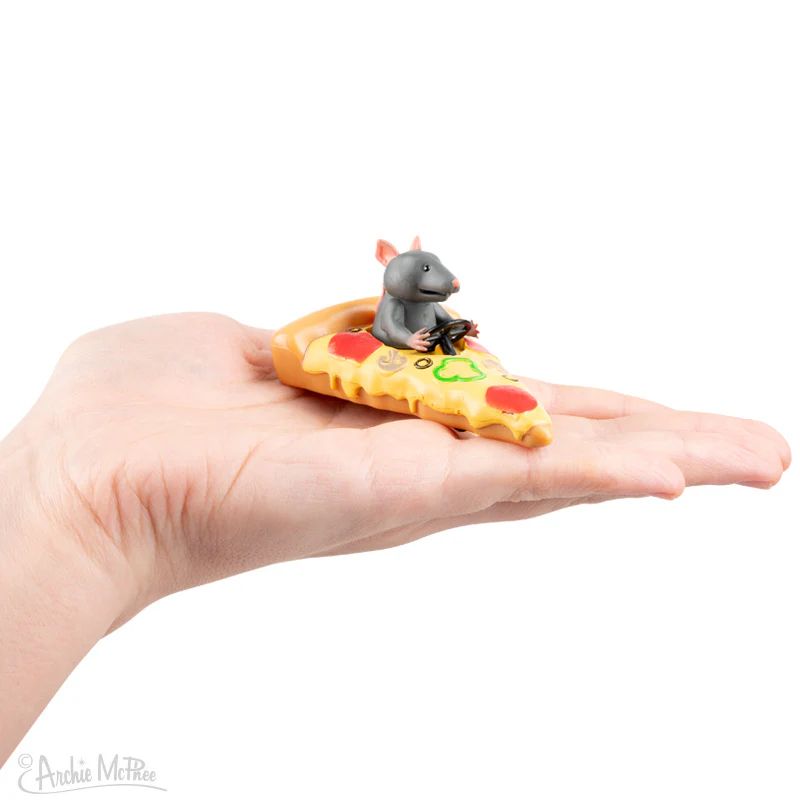 A hand holding a small toy of a rat driving a slice of pizza. The rat is holding a steering wheel. 