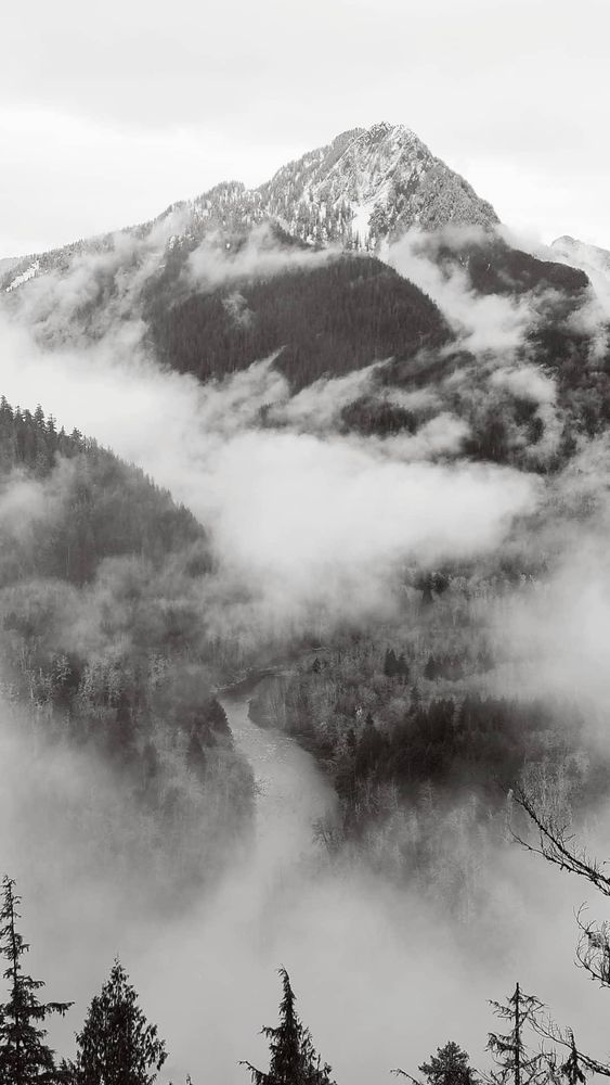 A mountain looms over a river valley shrouded in winter mist.