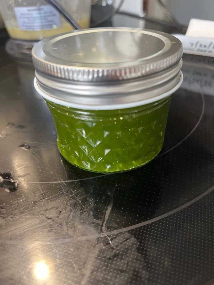 A small glass jar with basil oil 