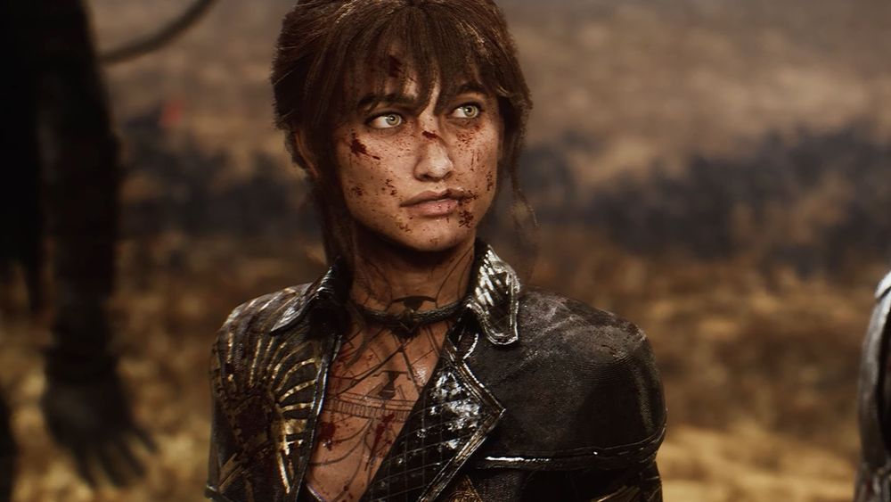 Woman with brown hair on ponytail. Black uniform with gold accents. Some tattoos on chest area 